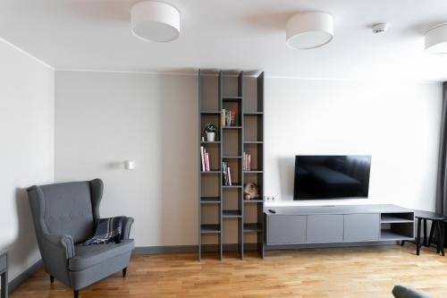 - un salon avec une télévision, une chaise et une étagère dans l'établissement Brand New, Family-friendly with a great location - Moon Apartment, à Ventspils