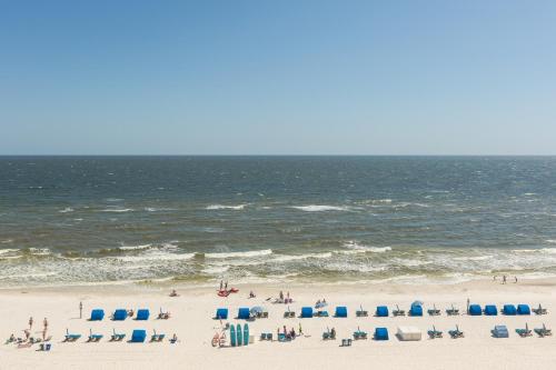 un grupo de personas en una playa con sillas y el océano en Seawind Condominiums, en Gulf Shores