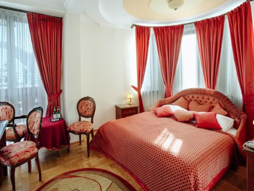 Pensjonat Klimek في موشينا: غرفة نوم بسرير احمر مع ستائر حمراء وكراسي