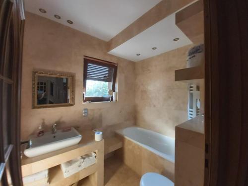 a bathroom with a tub and a sink and a bath tub at Domek pod Pobierowem in Gostyniec