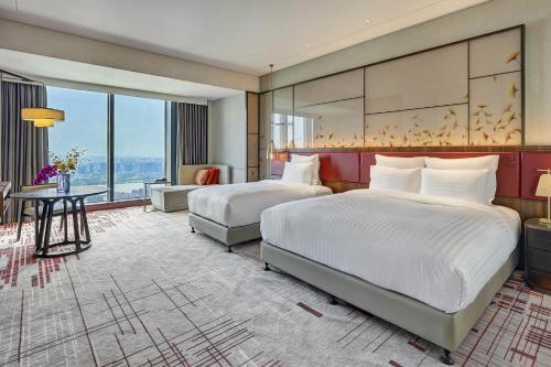 a hotel room with two beds and a table at Pullman Huizhou Kaisa in Huizhou