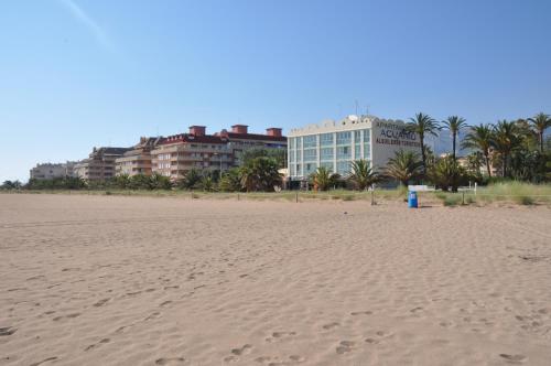 una playa de arena con edificios y palmeras en el fondo en Apartamentos Acuario, en Denia