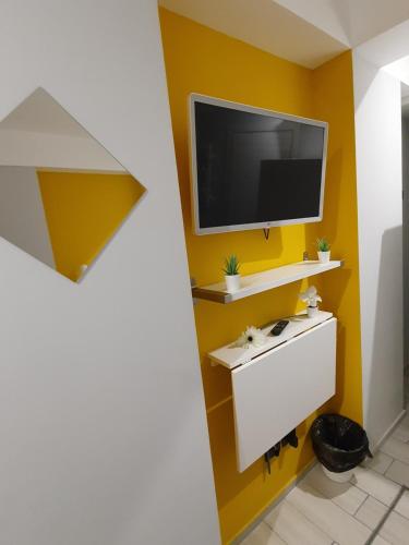een woonkamer met een tv aan een gele muur bij Scilla's Dream in Scilla