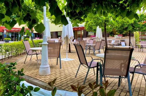 un patio con mesas, sillas y sombrillas blancas en Hotel Torremangana, en Cuenca