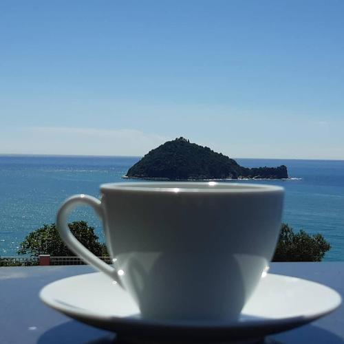 a white coffee cup sitting on a table with the ocean at Verde Mare in Alassio