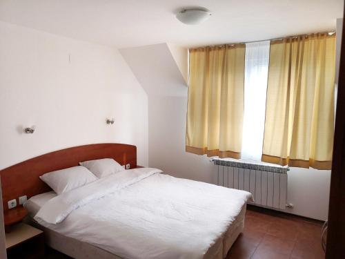 a bedroom with a bed with white sheets and a window at Hotel Zenit Satovcha in Satovcha