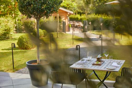 a table with wine glasses and a tree on a patio at Infinity Hotel & Conference Resort Munich in Unterschleißheim