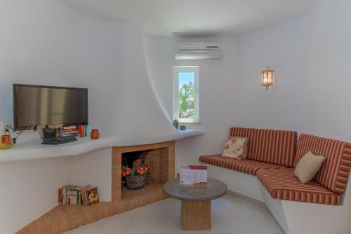 uma sala de estar com um sofá e uma televisão em FLH Balaia Village Apartment with Pool I nos Olhos de Água