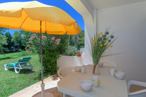 um guarda-chuva amarelo sentado numa mesa no quintal em FLH Balaia Village Apartment with Pool I nos Olhos de Água
