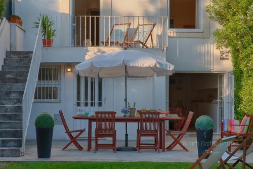 a table with chairs and an umbrella on a patio at Beach Golf & Garden House in Arcozelo