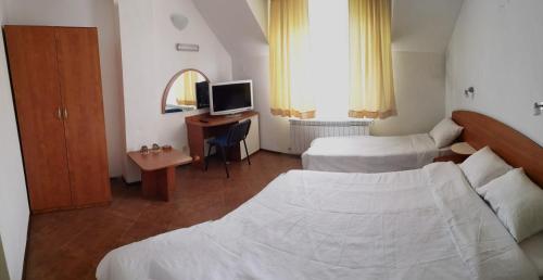 a bedroom with two beds and a desk with a television at Hotel Zenit Satovcha in Satovcha