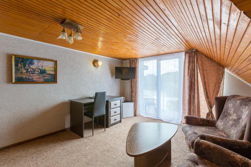 a living room with a couch and a desk and a window at Shepilska Relax Complex in Dovholuka