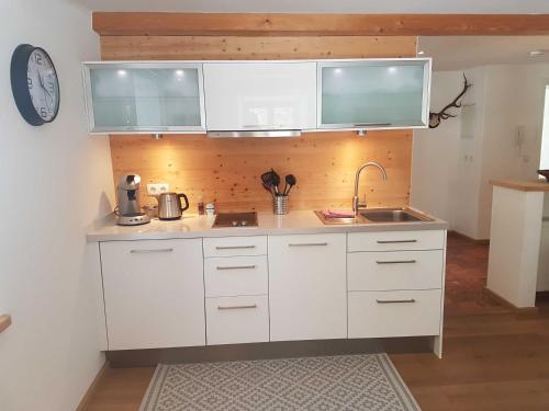 a kitchen with white cabinets and a sink and a clock at Ferienwohnungen Garhammer_ Kreuth_ in Kreuth