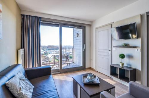 a living room with a couch and a large window at Evancy Etoile Des Dunes in Bray-Dunes