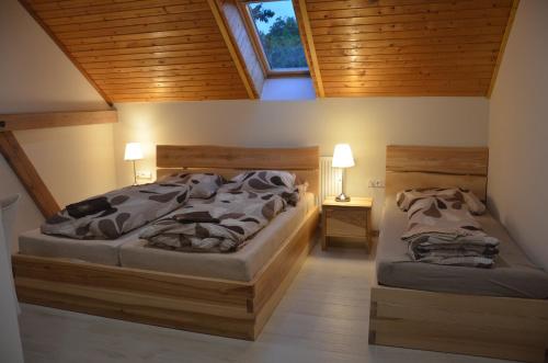 two beds in a bedroom with wooden ceilings at penzion U Koníčka in Strážiště