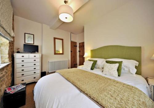 a bedroom with a large white bed and a dresser at Thornton in Chipping Campden