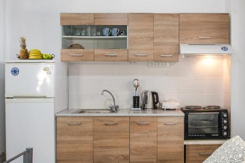 a kitchen with wooden cabinets and a white refrigerator at Bohemian Townhouse in Skiathos Town