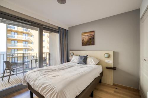 a bedroom with a large bed and a balcony at Evancy Etoile Des Dunes in Bray-Dunes