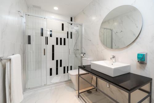 a white bathroom with a sink and a mirror at Tandem Puerto Chico in Cádiz