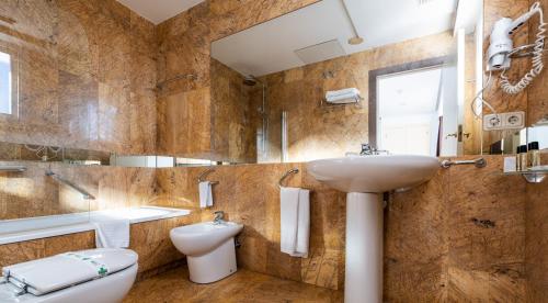 łazienka z umywalką, toaletą i lustrem w obiekcie Hotel Ciudad de Cazorla w mieście Cazorla