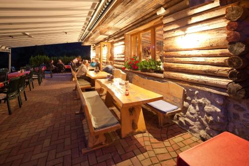 ヴァイトリングにあるAlpengasthof Oberweissbachの木製のテーブルと椅子、座り人が並ぶレストラン