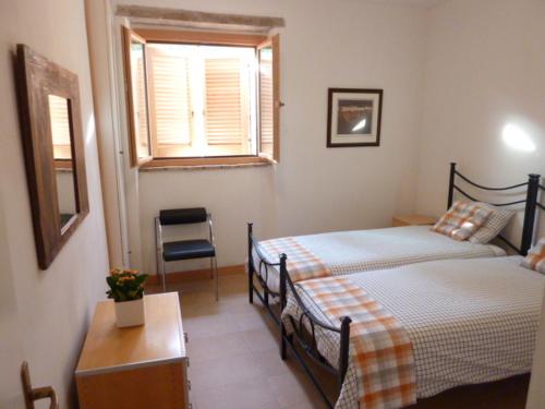 sypialnia z 2 łóżkami, oknem i krzesłem w obiekcie Casa sul Monte w mieście San Venanzo