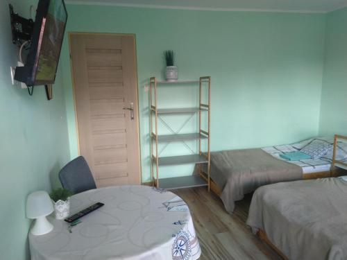 a room with two beds and a table and a desk at Pokoje Gościnne Bajka in Rumia