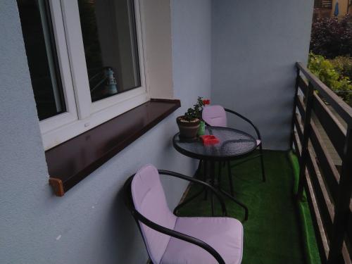 a small table and chairs on a balcony with a window at Pokoje Gościnne Bajka in Rumia