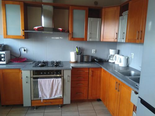 a kitchen with wooden cabinets and a stove top oven at Pokoje Gościnne Bajka in Rumia