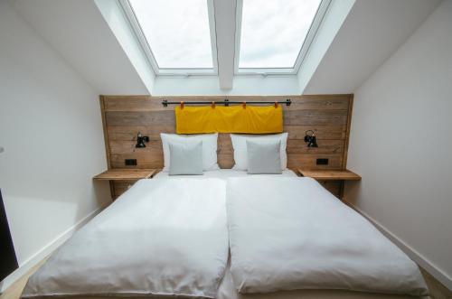 a bedroom with a large white bed with a skylight at Hotel Landhafen in Niebüll