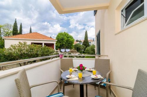 patio con mesa y sillas en el balcón en Apartments Eva, en Dubrovnik