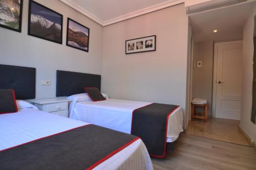 a hotel room with two beds and a door at Hostería El Bodegón De Gredos in Arenas de San Pedro