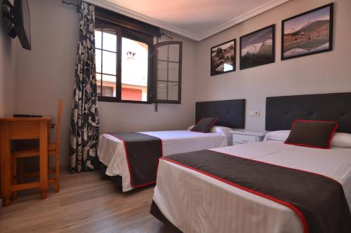 a hotel room with two beds and a window at Hostería El Bodegón De Gredos in Arenas de San Pedro