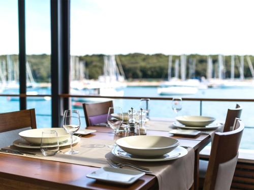 a wooden table with plates and wine glasses on it at Ribarska Koliba Resort in Pula