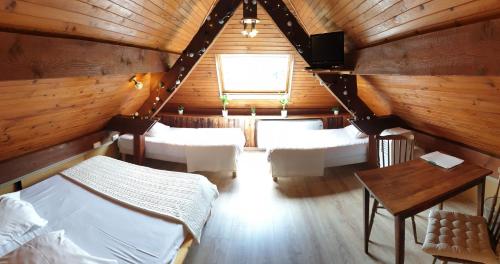 a attic room with beds and a table and a window at Auberge de la Rivière in Foncine-le-Haut