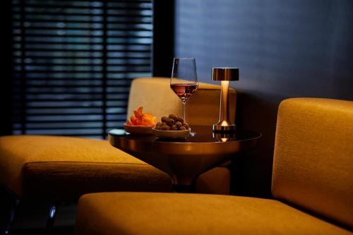 a glass of wine and a bowl of fruit on a table at Infinity Hotel & Conference Resort Munich in Unterschleißheim