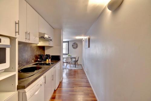 une cuisine avec des placards blancs et un long couloir dans l'établissement LE SAINT-MICHEL - Appartement Cosy, à Bordeaux