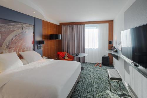 a hotel room with a bed and a flat screen tv at Hotel Mercure Toulouse Centre Compans in Toulouse