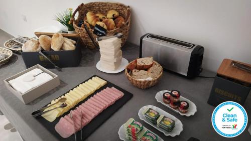 a table topped with cheese and bread and baskets of bread at Coudelaria Residence in Foz