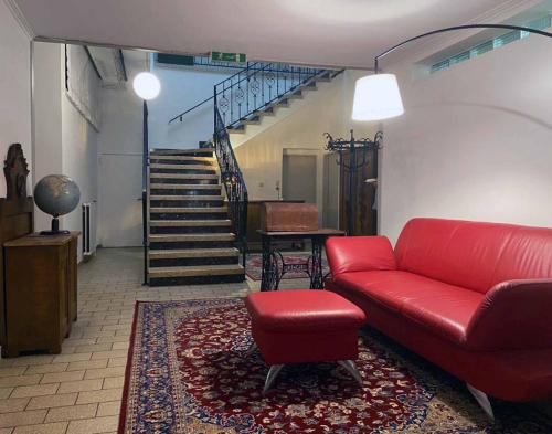 a living room with a red couch and a staircase at Bühnenwirtshaus Juster in Gutenbrunn