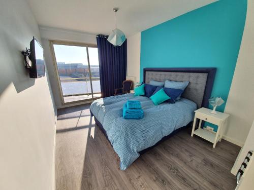 een slaapkamer met een bed met blauwe kussens en een raam bij L'épopée Panoramique - Parking - Avenue de Champagne - Epernay in Épernay