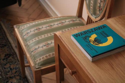a book sitting on a wooden table next to a chair at Chopin Boutique in Warsaw