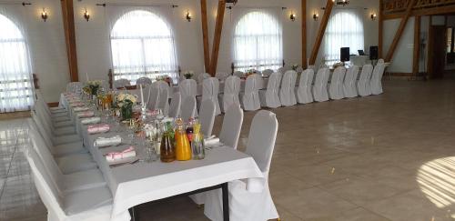una sala con tavoli e sedie bianchi in una sala di Grochowiak a Grochów