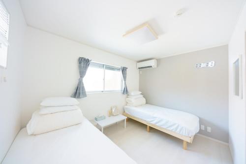 2 bedden in een witte kamer met een raam bij Osaka Yeon House in Osaka