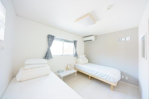 two beds in a white room with a window at Osaka Yeon House in Osaka