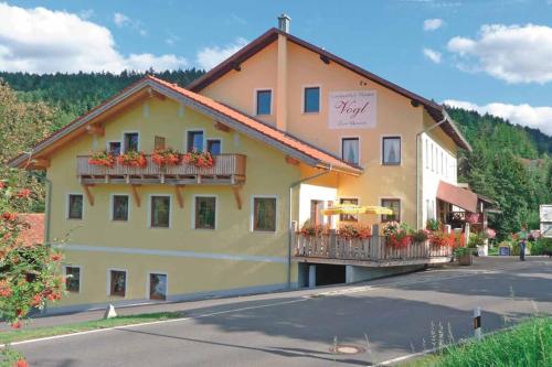 a building with flowers on the balconies on a street at Landgasthof Vogl - Zum Klement in Neukirchen beim Heiligen Blut