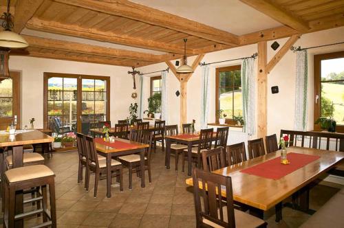 un restaurante con mesas y sillas de madera y ventanas en Landgasthof Vogl - Zum Klement, en Neukirchen beim Heiligen Blut