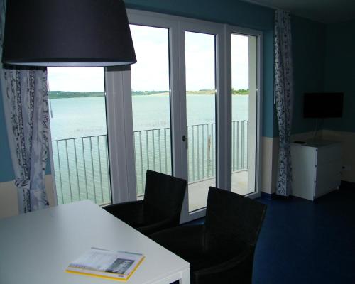 a room with a table and chairs and a large window at Laguna Seeappartements in Neukieritzsch