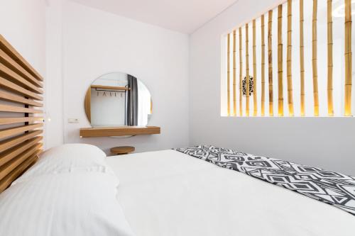 a white bedroom with a bed and a tv at Golden Beach Hotel in Chrissi Akti