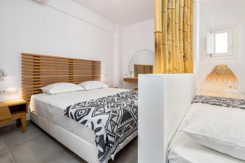 a white bedroom with two beds and a table at Golden Beach Hotel in Chrissi Akti